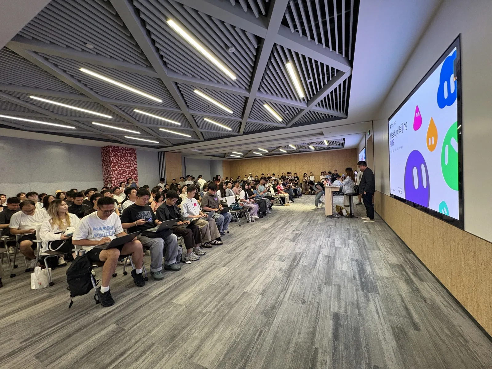 A packed room at Grok Bot Meetup Beijing, with the event slide on a large screen